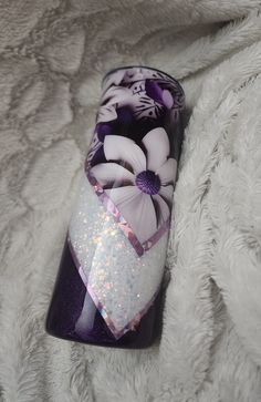 a purple and white case with flowers on it sitting on a fluffy surface next to a blanket