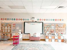 a room with lots of furniture and decorations on the walls, including a large whiteboard