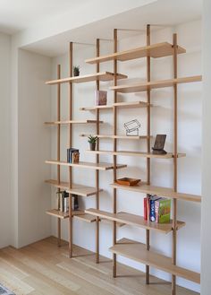 a wooden shelf with books on it in a living room next to a white wall