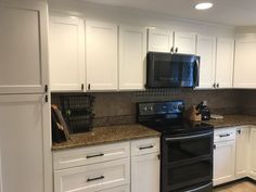 a kitchen with white cabinets and black appliances