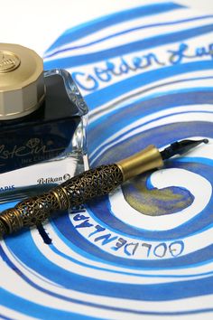 a fountain pen sitting on top of a blue and white paper