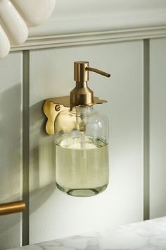 a soap dispenser hanging on the wall next to a light fixture in a bathroom