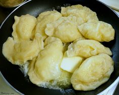 some dumplings are cooking in a black skillet on the stove top next to a bottle