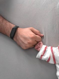 a man holding the hand of a baby who is wrapped in a blanket with a wristband