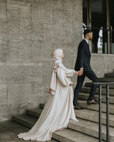 a man and woman walking up some steps together, dressed in muslim garb holding hands