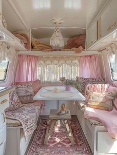 the inside of a camper with pink curtains and white table in front of it