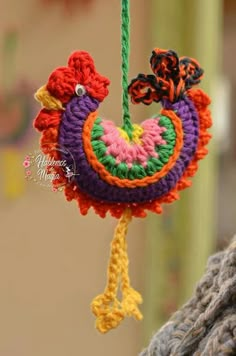 a crocheted ornament hanging from a rope with two birds on it