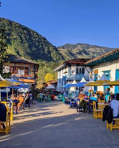 people are sitting at tables in the middle of an open air area with mountains in the background