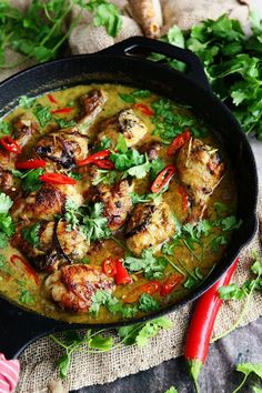 a skillet filled with chicken and vegetables on top of a cloth next to some parsley