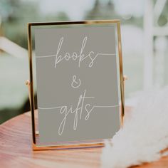 a sign that says books and gifts on it sitting on a table next to feathers