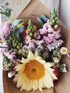 a bouquet of flowers sitting on top of a piece of brown paper next to a wooden door