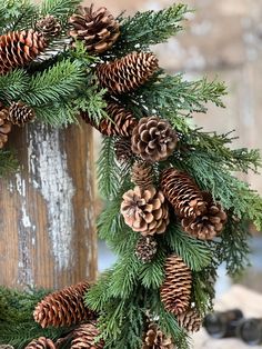 a pine cone wreath is hanging on a wooden post