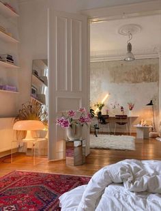 a bed sitting in a bedroom next to a white wall with flowers on top of it