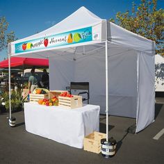 a white tent with fruit on it in a parking lot