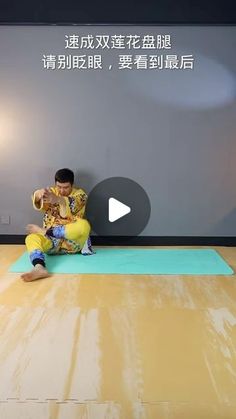 a man sitting on top of a yoga mat in front of a wall with chinese writing