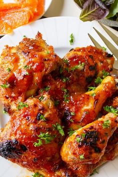 a white plate topped with chicken wings covered in bbq sauce and garnished with parsley