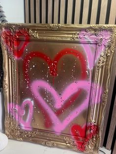 a painting with pink and red hearts in a gold frame