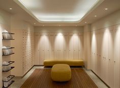 a room with several lockers and a bench in the middle is lit by recessed lights