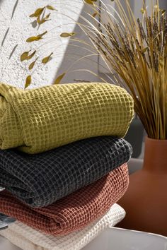 towels stacked on top of each other next to a potted plant