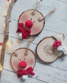 three wooden ornaments with red bows and reindeer heads on them, hanging from a tree branch