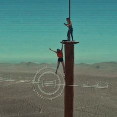 two people standing on top of a tall pole in the middle of a desert area