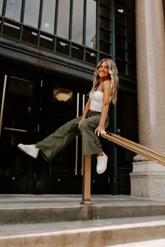 a woman is sitting on the steps in front of a building and posing for a photo