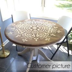 a round table with white chairs and a candle on the floor in front of a window