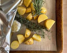 potatoes and herbs on a cutting board with foil