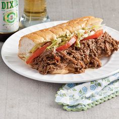 a plate with a sandwich on it next to a bottle of beer