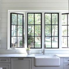 a kitchen with white cabinets and black windows