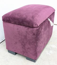 a large purple ottoman sitting on top of a white tile floor next to a wall