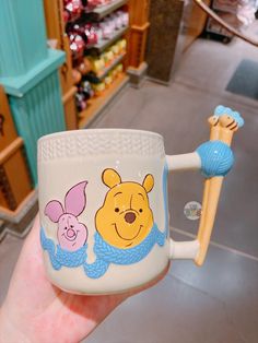 a hand holding a winnie the pooh mug