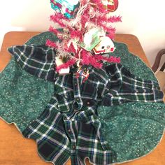 a small christmas tree with ornaments on it sitting on top of a green table cloth