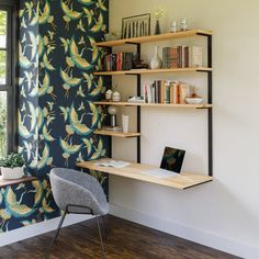 a laptop computer sitting on top of a wooden desk next to a book shelf filled with books