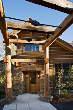 the front entrance to a log cabin with stone pillars and columns on each side, along with a walkway leading up to it