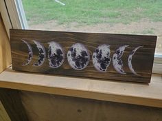 three phases of the moon are displayed on a wooden shelf in front of a window