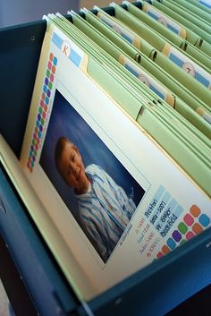 a blue file box filled with lots of folders next to a baby's face