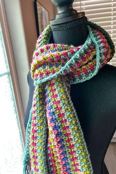 a multicolored crocheted scarf on top of a mannequin