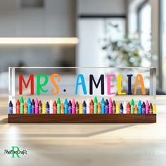 an acrylic sign that says mrs amella with crayons in it