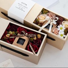 two boxes that have flowers in them on a white counter top and one has a ribbon around the box