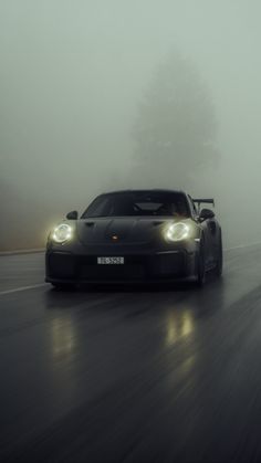 a black sports car driving on a foggy road