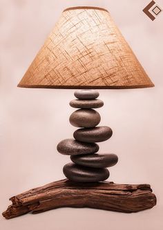 a lamp made out of rocks sitting on top of a piece of drifty wood