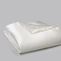 an unmade bed with white sheets and pillows on top of it, in front of a gray background