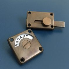 two metal latches on top of a blue surface with the word vacant printed on them