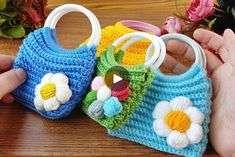 two crocheted purses with flowers on them are being held by someone's hands