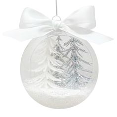 a glass ball ornament with snow covered trees in the center and a white bow on top