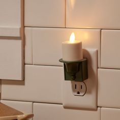 a lit candle is on the wall next to a light switch