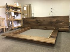 a bed frame made out of wood in a room with shelves and other items on the wall