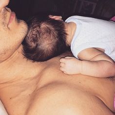 a man laying in bed holding a baby