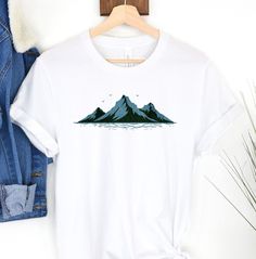 Mountains and Lake T-shirt Materials: Sweatshirts and hoodies are made of 50% cotton and 50% polyester. T-shirts in solid colors are 99% cotton and 1% polyester, while t-shirts in heather and blended colors are 52% cotton and 48% polyester. Cancellations: Accepted within 2 hours of your purchase. Shipping: Orders typically ship within 4 business days, though most are shipped the next day. Once the order ships, delivery usually takes 1-5 days depending on your location. Returns/Exchanges: All orders are made-to-order, so we do not accept returns or exchanges. However, please contact us if you have any issues with your order. Care Instructions: Machine wash cold, tumble dry on low heat. Do not dry clean or iron the design directly. Thank you for shopping with Luveana! Mountain Tee, Mountain Tshirt, Minimalist Shirts, Blue Mountain, Gifts For Nature Lovers, Unisex Shirts, Festival Season, Sweat Shirt, Gender Neutral